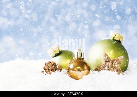 Un cono di fuoco e tre palline di Natale sulla neve con sfondo sfocato blu morbido e neve che cade Foto Stock