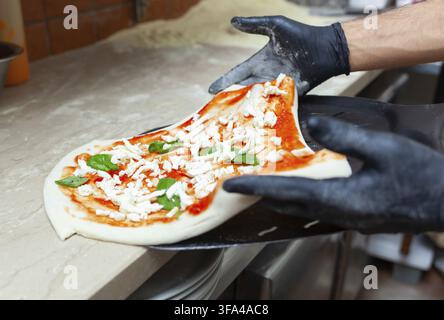 Pizza margherita cruda messa su una pala da forno per la cottura Foto Stock