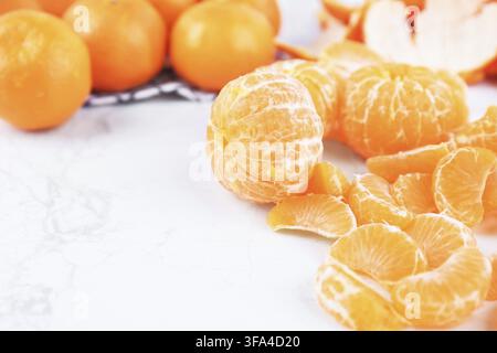 Mandarini sbucciati e segmenti di arancia fresca su uno sfondo di marmo bianco con spazio libero Foto Stock