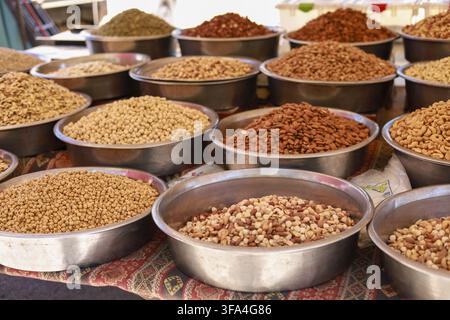 Diverse noci e semi presentati in ciotole di metallo su uno stand di mercato Foto Stock