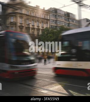 Praga, ceco - 1 maggio 2023: Un uomo che usa il cellulare in un ambiente occupato con persone che camminano e tram in primo piano. stile di vita frenetico conce Foto Stock