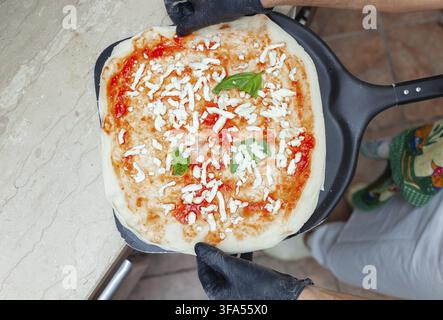 Pizza margherita cruda messa su una pala da forno per la cottura Foto Stock