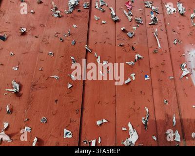 Bache pubblica in legno dipinta di marrone rossastro con piccoli pezzi di carta e graffette Foto Stock
