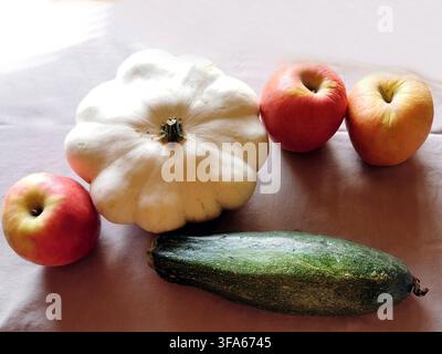 Tre mele Malus domestica, una zucca bianca Cucurbita pepo e una zucchina Cucurbita pepo su una superficie piatta. Produzione mista. Bsip 016974 016 Foto Stock