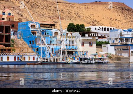 Colorati ospiti nubiani e hotel sulle rive del Nilo vicino a Assuan, Egitto, con architettura nubiana tradizionale, facciate dipinte e bo Foto Stock
