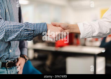 Incontro di lavoro tra due professionisti che si stringono la mano in un ambiente d'ufficio moderno durante il pomeriggio Foto Stock