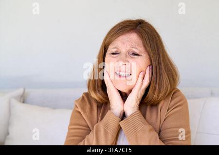 Donna anziana che sperimenta dolori ai denti o al mascello, problemi di salute e cure dentali negli anziani, disagio e processo di invecchiamento, concetto di assistenza sanitaria a domicilio. Più anziana a Foto Stock