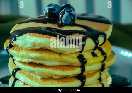 Pila di pancake soffici con sciroppo di cioccolato e mirtilli Foto Stock