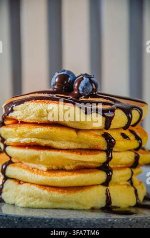 Pila di pancake soffici con sciroppo di cioccolato e mirtilli Foto Stock