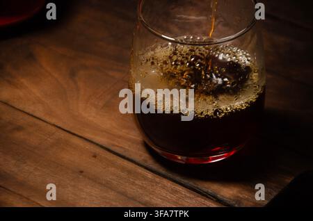 Versare caffè in un bicchiere su un tavolo di legno rustico scuro Foto Stock