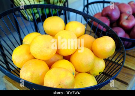 Ciotola traboccante di arance fresche e mele rosse in cesti di filo metallico nero su superficie di legno. Sopot. Polonia. Cestino di frutta Bsip 016983 1097 Foto Stock