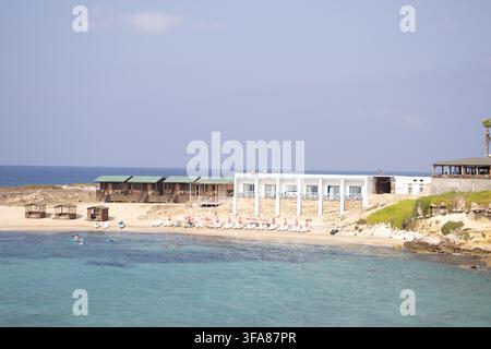 Hotel e ristorante Oasis sulla spiaggia di Ayfilon. Dipkarpaz. Vista costiera sulle rovine storiche in pietra, resort sul lungomare. Foto Stock