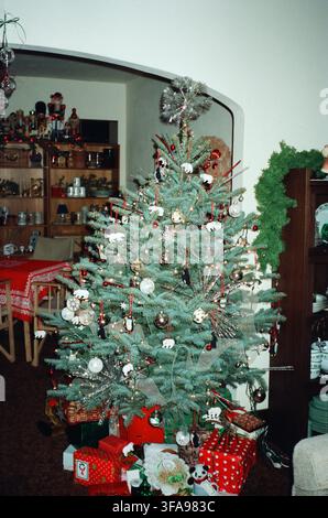 Un albero di Natale completamente addobbato con ornamenti di orsi polari, palline e una stella di lametta sulla cima, circondato da regali incartati in un caldo soggiorno familiare Foto Stock