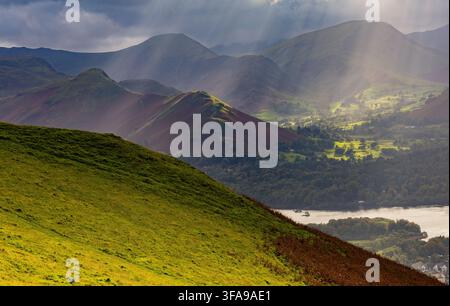 Raggi di sole drammatici che si fanno strada tra le nuvole su Keswick, Derwentwater e le colline ondulate del Lake District National Park, Cumbria, Regno Unito. Foto Stock