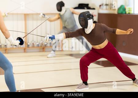 Un gruppo di recinti si allena in duelli e fa uscire i colpi sui cuscini in palestra Foto Stock
