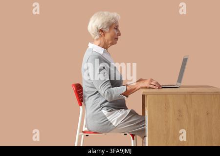 Anziana che utilizza un laptop inclusione digitale e invecchiamento sano persona anziana che impara la tecnologia isolata su uno sfondo da studio Foto Stock