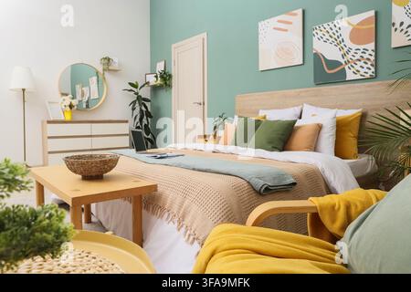 Lavoro remoto e configurazione dell'ufficio domestico, laptop sul letto in una camera da letto moderna con arredamento elegante e piante Foto Stock