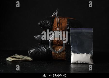 Pacchetti di farmaci con manette su sfondo scuro Foto Stock