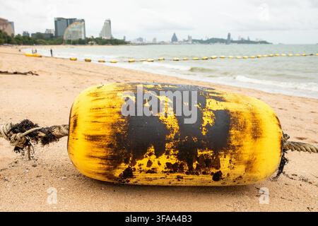 Boia e corda ricoperte di residui di petrolio greggio spiaggiate su una spiaggia sabbiosa, concetto di inquinamento da fuoriuscita di petrolio marino e disastro ambientale Foto Stock