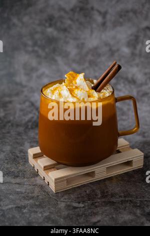 Latte speziato di zucca per riscaldare il caffè al mattino. Bevande autunnali per Halloween, giorno del Ringraziamento, bevanda autunnale piccante alla cannella, bevande calde di stagione in un'accogliente tazza d'arancia. Atmosfera di fredde giornate piovose natura morta Foto Stock