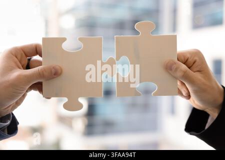 Primo piano delle mani di due professionisti aziendali che impilano i pezzi del puzzle insieme Foto Stock