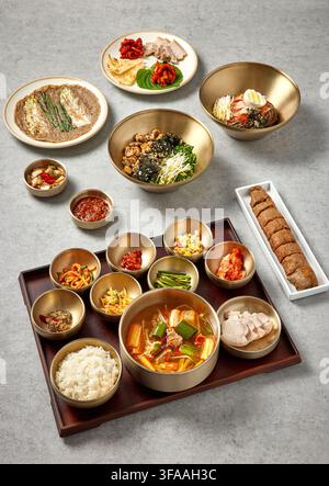 Pasto completo tradizionale coreano con stufato di pasta di fagioli neri Doenjang Jjigae, riso e assortiti piatti di accompagnamento Banchan in ciotole dorate su un vassoio di legno, Cor Foto Stock