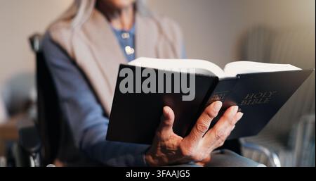 Bibbia, mani e donna anziana in sedia a rotelle a casa per la religione, il culto o la guida spirituale. Rilassamento, lettura e persona anziana con disabilità in Foto Stock