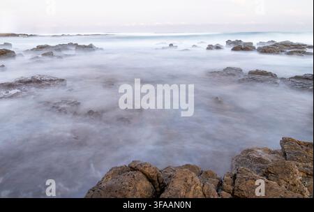 Immagine astratta d'atmosfera a lunga esposizione di onde che si infrangono su una costa rocciosa. Foto Stock