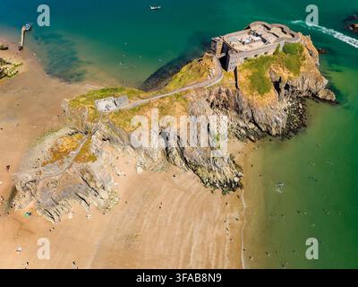 Vista ad angolazione alta di una fortezza su isola tidale collegata da una passerella, promontorio di calcare roccioso che incontra l'oceano costiero limpido su una spiaggia estiva Foto Stock