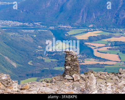 Vista aerea del picco montuoso Kongen con un prominente cumulo di pietre che si affaccia sulla rigogliosa valle verde e il fiume sottostante ad Andalsnes, More og Roms Foto Stock