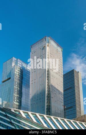 Vista ad angolazione bassa di moderni grattacieli in vetro contro un cielo blu limpido nella città di Shenzhen, Cina. Architettura aziendale contemporanea. Finanza, affari Foto Stock