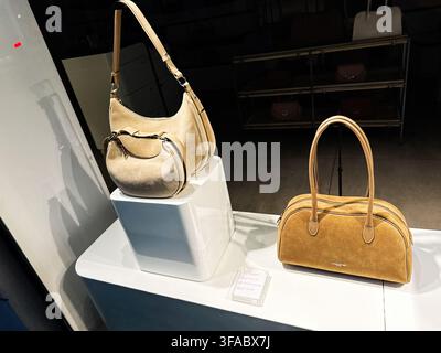 Parigi, Francia – 14 maggio 2026: Eleganti borse Lancaster in pelle scamosciata marrone chiaro esposte su piedistalli bianchi nella vetrina di una boutique parigina per gli acquirenti di moda di lusso Foto Stock