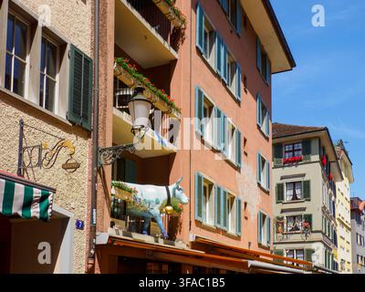 Un edificio a Zurigo sembra ospitare una mucca bianca vista su un balcone sopra il ristorante sottostante Foto Stock
