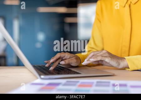 Foto ravvicinata di una parte del corpo, mani femminili di una donna seduta a un tavolo che digita sulla tastiera di un laptop. Foto Stock