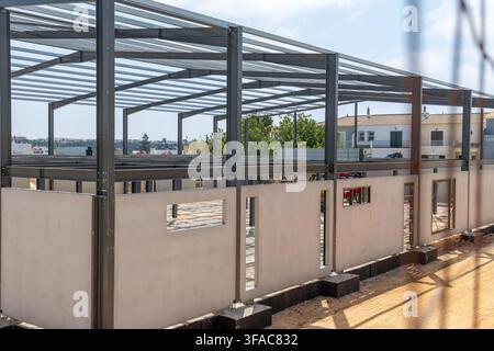 Una struttura moderna di edificio viene eretta con una visibile impalcatura in acciaio e elementi di muro in cemento prefabbricato Foto Stock