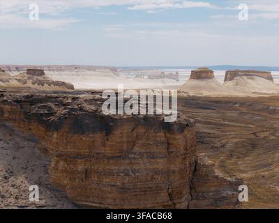 Veduta aerea delle drammatiche formazioni rocciose in calcare e dei canyon di Bozhira, con scogliere stratificate e vaste pianure desertiche nel distretto di Karakiya, Ma Foto Stock