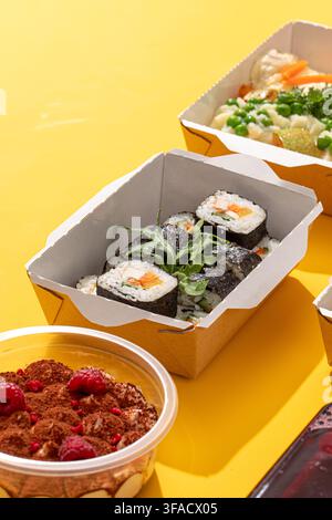Rotoli di sushi in scatola di consegna di carta su giallo Foto Stock