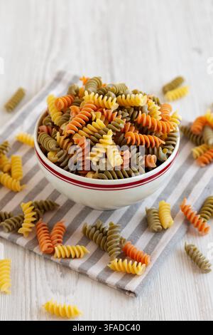 Pasta secca biologica tricolore fusilli in una ciotola, vista laterale. Foto Stock