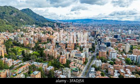 Una prospettiva aerea mostra il vasto paesaggio urbano di Bogotá, incorniciato dalle rigogliose colline orientali sotto un cielo parzialmente nuvoloso. Foto Stock