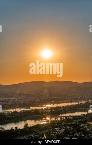 Tramonto luminoso sul fiume Danubio e panorama di Vienna con colline all'orizzonte Foto Stock