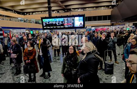 Passeggeri in attesa sotto i tabelloni delle partenze alla stazione londinese di Euston, che illustrano l'affollamento e l'incertezza in un importante terminal di Network Rail. Foto Stock