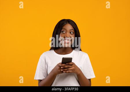 Sorridente afroamericana utilizzando il telefono cellulare Foto Stock