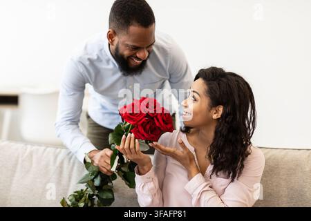 Giovane uomo nero che dà rose rosse alla donna Foto Stock