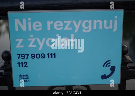 Segnale blu della linea di assistenza per la prevenzione del suicidio sulla ringhiera del ponte con la scritta „Nie rezygnuj z zycia“ che significa „Non rinunciare alla vita“ con l'emblema della città di Danzica. Foto Stock
