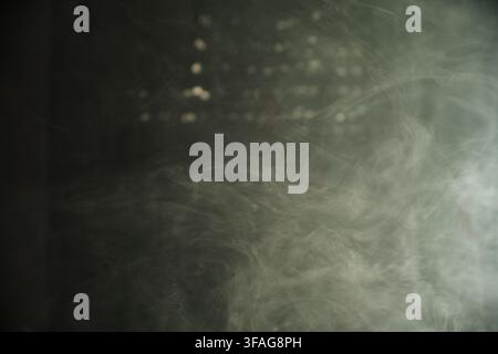 Sfondo astratto con fumo bianco vorticoso e vapore che fluttua su uno sfondo scuro textureggiato con luci sfocate e morbide. Foto Stock
