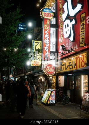 Insegne di ristoranti illuminate e facciate di izakaya lungo una strada a Dotonbori di notte, Osaka, Giappone Foto Stock