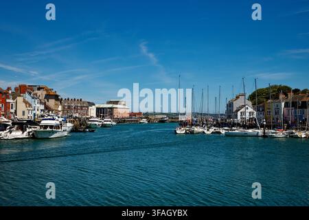 Barche e yacht ormeggiati nelle acque blu di un porto sul fiume Wey, Weymouth, Dorset, Inghilterra. Foto Stock