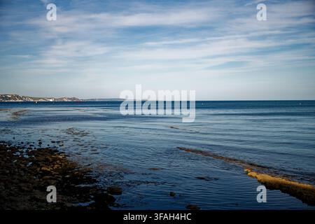 Morbide onde si infrangono su una costa rocciosa da un mare blu con una linea costiera di scogliere di gesso bianche in lontananza, Weymouth, Dorset, Inghilterra. Foto Stock