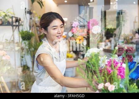 Fiorista coreana che sistema un bouquet colorato nel suo negozio di fiori Foto Stock