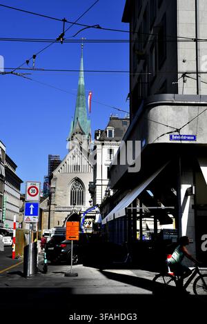 La chiesa di San Pietro a Zurigo, Svizzera, appare sullo sfondo di questa veduta stradale, riconoscibile per il suo distinto campanile verde e il grande orologio Foto Stock
